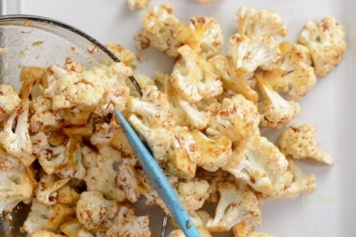 Putting marinated cauliflower on baking sheet pan